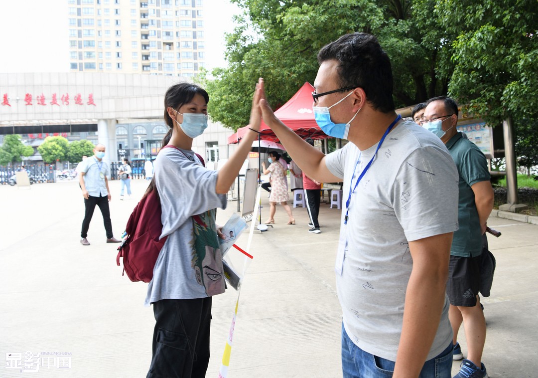 7月7日，安徽淮南二中高三(27)班学生李星洁走进考场前与学校送考老师击掌加油。