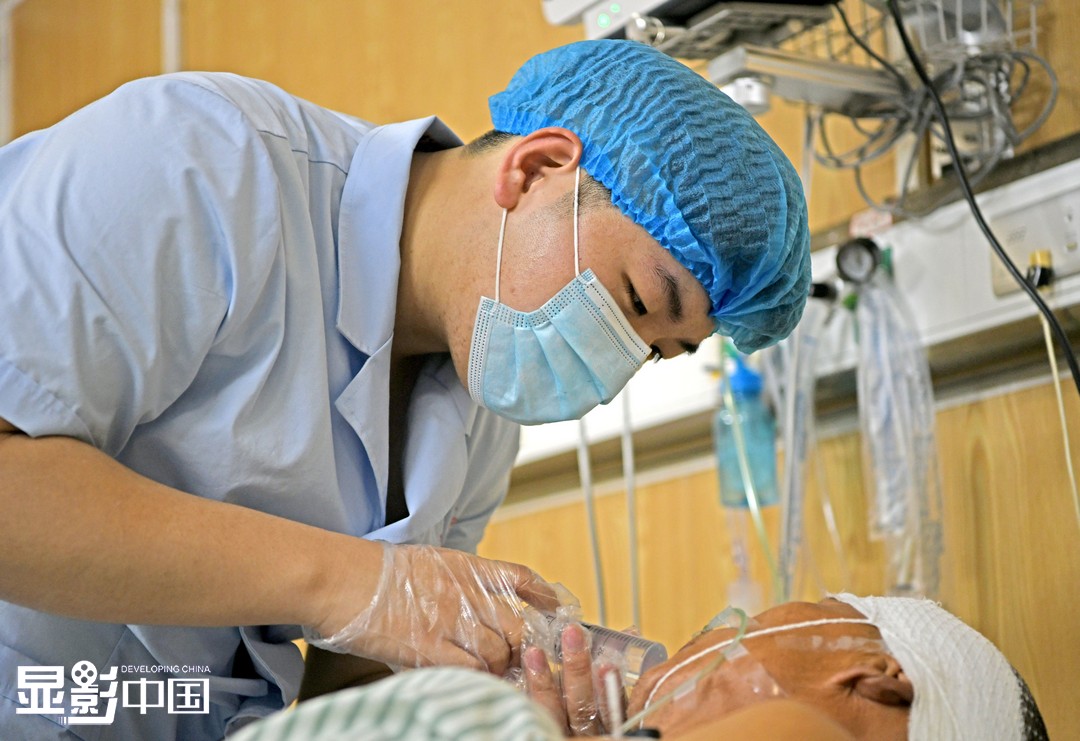 5月10日凌晨，安徽理工大学第一附属医院神经重症监护病房内，夜班中的“00后”男护士段青龙为患者进行喂水护理。