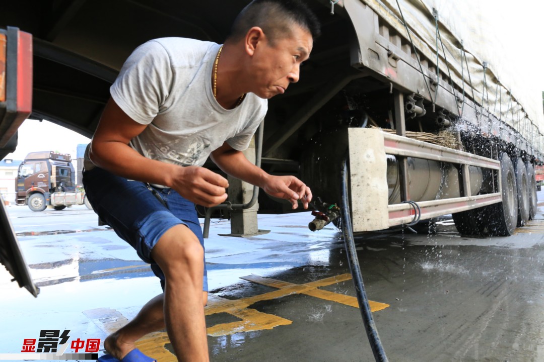 货车行驶3小时后，周自忠停靠在服务区给车子加水,检查车况。新华网 卢志佳 摄