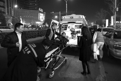 前晚，在国瑞城门口的非机动车道上，急救人员将一名病人推上120急救车。新京报记者 王嘉宁 摄