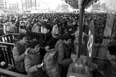 昨天下午3点多，在北京站前广场，大批旅客排队等候进站，一名车站工作人员在现场引导，确保旅客顺利进站。京华时报记者徐晓帆摄