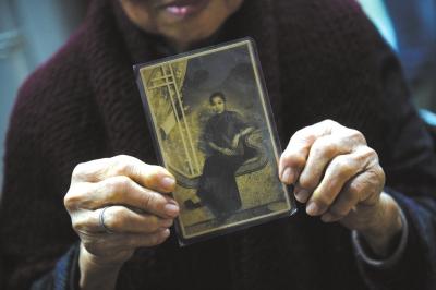 90岁黄月蓉为记者介绍当年在新加坡当妈姐时拍下的照片。