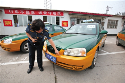 2014年7月4日，交通执法人员展示套牌出租车，与旁边的真出租车相比，套牌车左前方保险杠无字母数字编号。新京报记者 高玮 摄