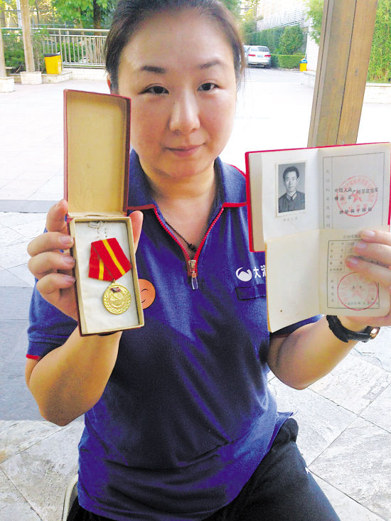 李文仁小女儿展示父亲的立功徽章和证书