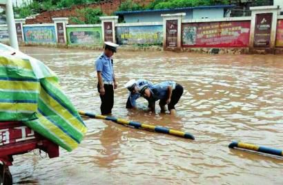 古蔺交警冒雨清掏排水口的场景，被网友点赞。