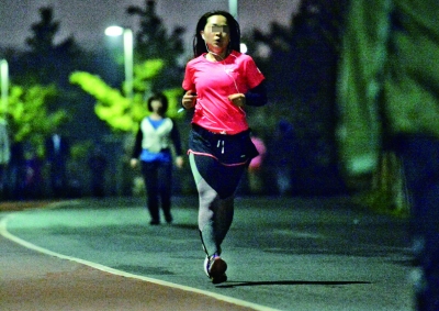 奥森公园夜跑者戴着耳机边听音乐边跑步