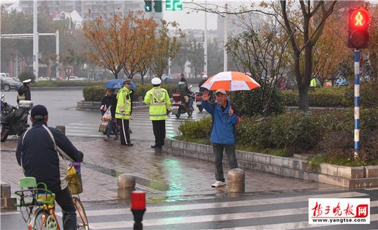退休老人雨中撑伞劝行人不要闯红灯