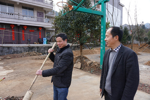 村支书金新光（左）与村主任金国明（右）正组织村民清理春节期间放鞭炮留下的垃圾