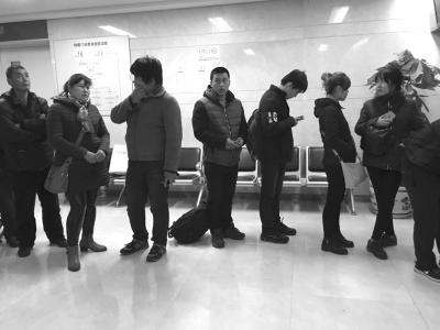 身穿黄色衣服的队长(左三)在排队取号。