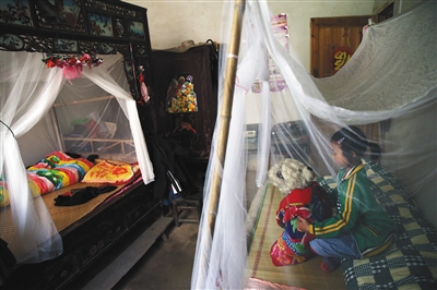 莎莎抱着玩具熊在自己的床上玩，自从查出艾滋病后，她不再跟姐姐同床睡觉，在房里又摆了张小床。