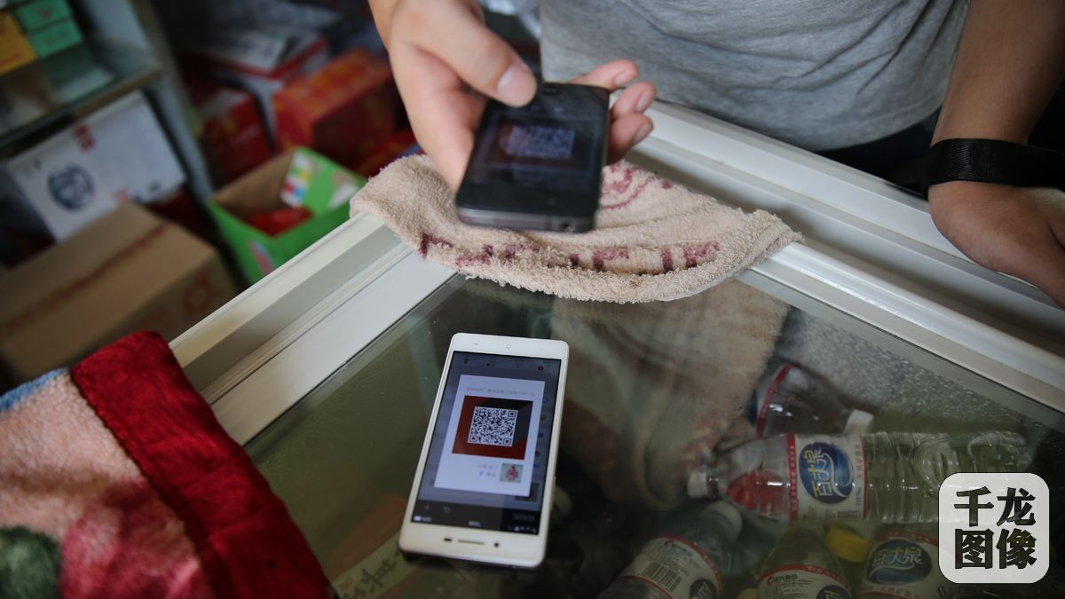 兴国县杰村乡含田村的&ldquo;农家书屋+电商&rdquo;服务站维护员的刘维清正与客人进行微信付款