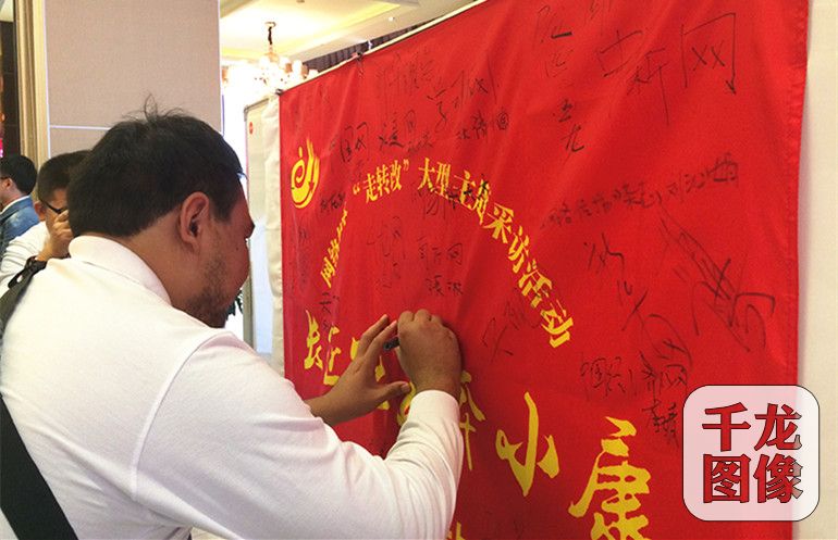 参加“长征路上奔小康”大型主题采访活动甘肃站的网络媒体记者在红旗上签下自己的名字。千龙网记者 马文娟 摄_副本
