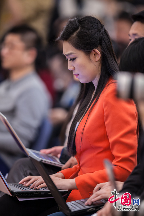  2015年3月7日，环保部长陈吉宁就&ldquo;全面加强环境保护&rdquo;答记者问，一名身穿橙红小西装的女记者在新闻发布会上紧张地写稿。中国网 郑亮 摄