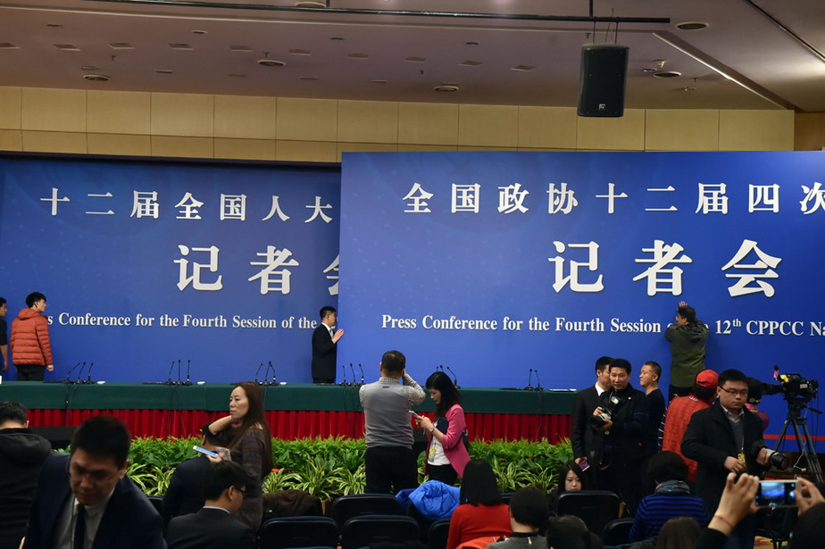 3月11日，工作人员正在抓紧更换背景板。（人民网记者 翁奇羽 摄）