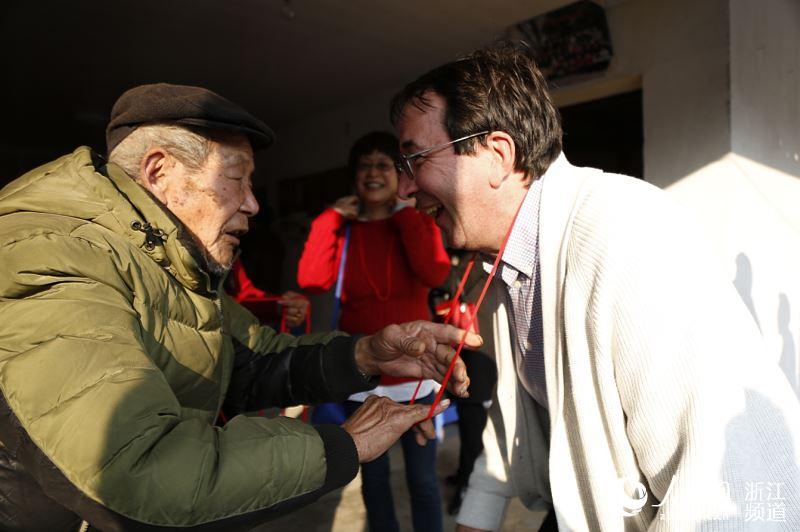 已故长寿老人朱土花的大儿子为外商挂上红绳以示吉利。胡余灶 摄