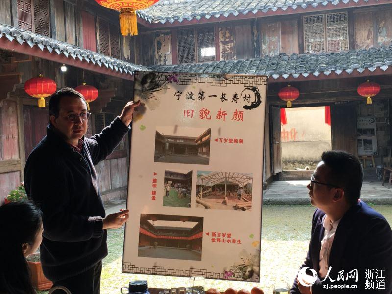 丁一牧向客人介绍河洪村村庄改造前后对比。陈金莲 摄