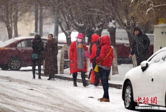 图为强降雪天气中，民众在车站等待公交车。中新社记者 刘新 摄