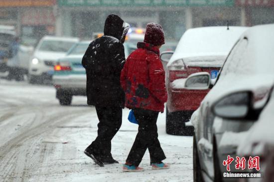 图为两位老者在雪中行走。中新社记者 刘新 摄