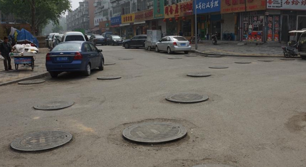 济南一马路近百井盖突然抬高 骑车路过如驾校“路考”