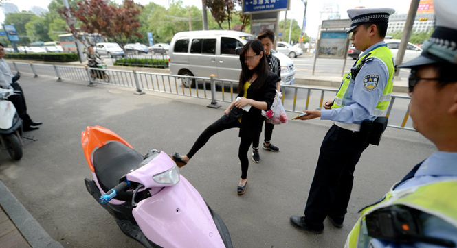 90后女大学生无证驾驶摩托被查 发飙将车踹倒