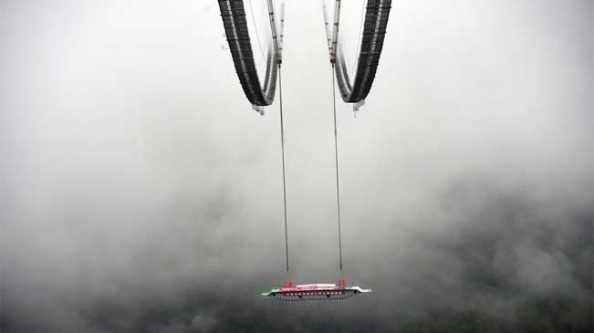 亚洲最大的山区悬索桥第一节段钢箱梁吊装成功