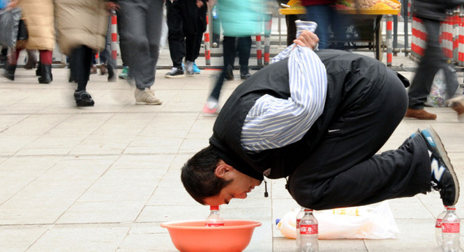 浙江街头一男子跪饮料瓶上乞讨 吸引路人眼球