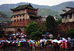 游客在凤凰古城北门城楼下冒雨等待乘船游览