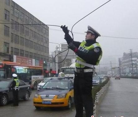 安徽一交警雨中托举电缆让车辆通过