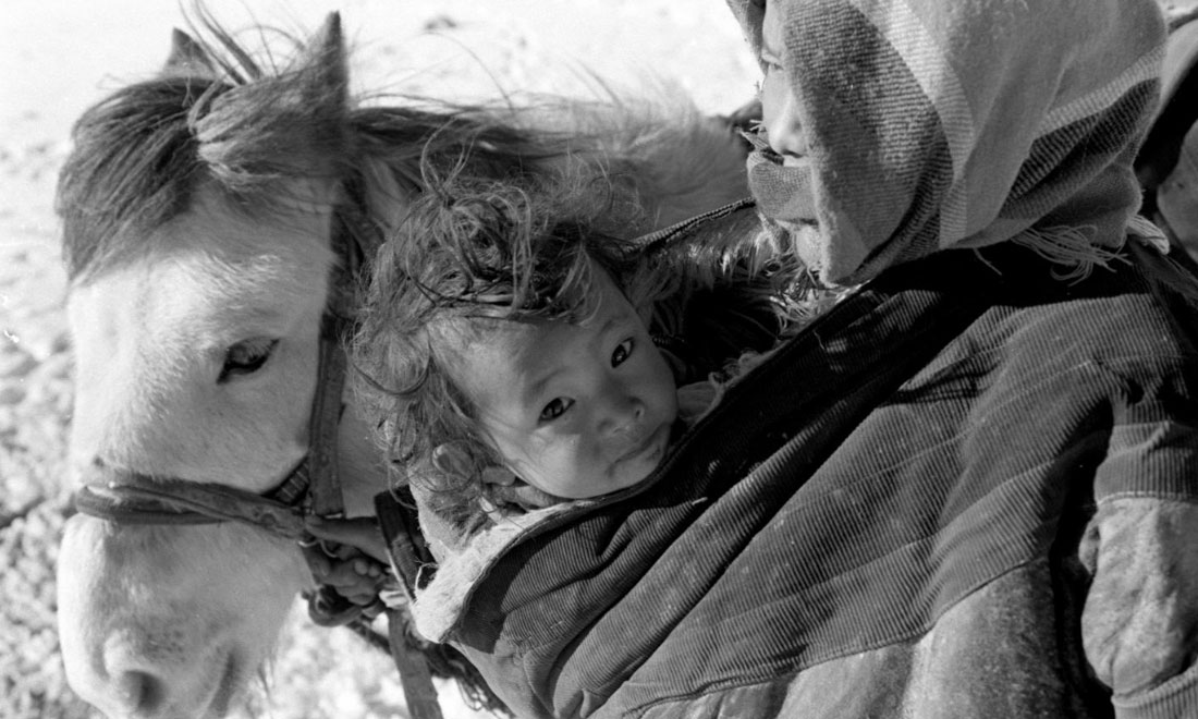 1990年3月，西藏当雄县纳木湖乡三村女牧民斯卓不畏严寒，怀抱幼子，准备到远处放牧。新华社记者觉果摄