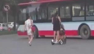 安全这根弦！ 女子脚踩平衡车手推婴儿车马路上穿行