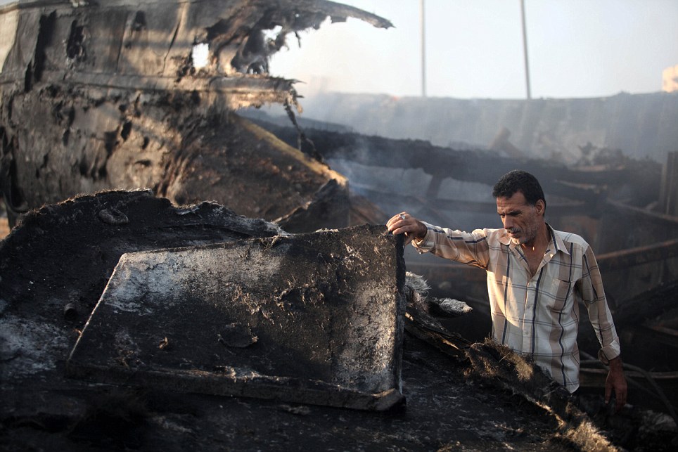 图为一名巴勒斯坦男子看着被摧毁的船。