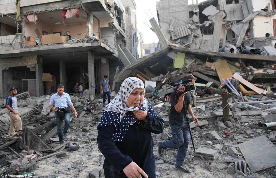 图为巴勒斯坦民众在以色列空袭后在一片废墟中寻找伤员。