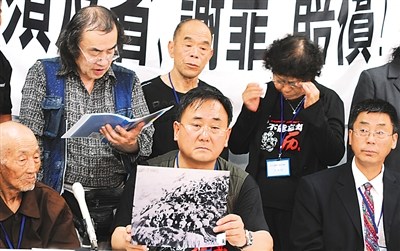 6月26日，在日本大阪，劳工遗属韩建国(前中)在记者会上展示反映花冈劳工惨状的照片。新华社记者　马兴华摄