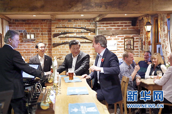 这是会晤结束后，习近平在卡梅伦陪同下乘车前往当地小镇体验酒吧文化。新华社记者 鞠鹏 摄