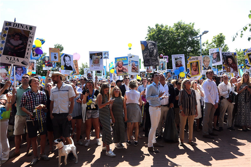 亲朋好友举着毕业生小时候的照片等待在校门口。庞其铭摄