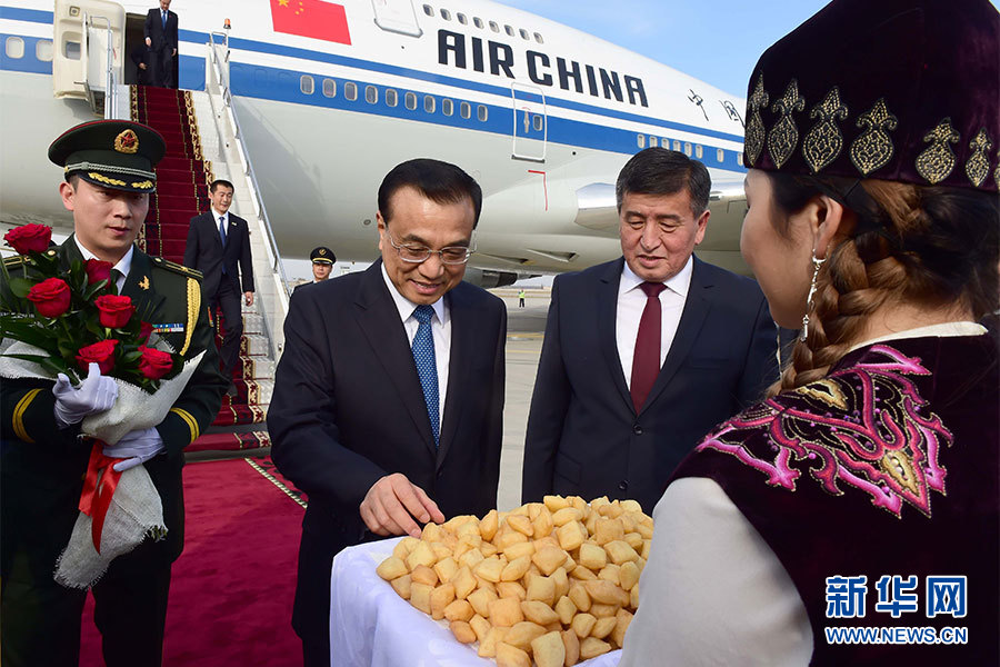 这是吉尔吉斯斯坦青年献上鲜花并请李克强总理品尝传统风味点心。新华社记者 张铎 摄