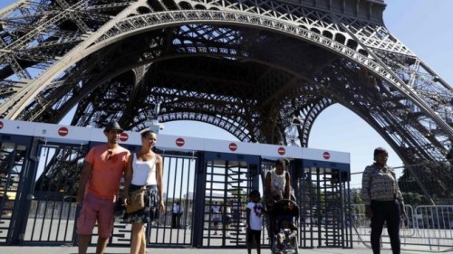 资料图:游客在埃菲尔铁塔前留影。