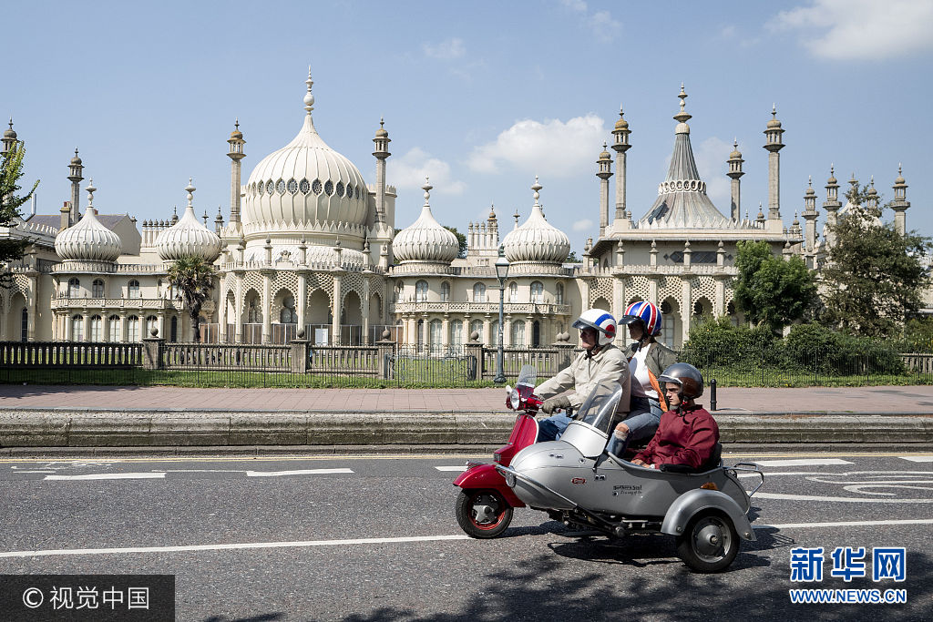 当地时间2017年8月27日，英国布赖顿，当地举行&ldquo;摩登派周末集会&rdquo;，民众骑摩托车参加。***_***BRIGHTON, ENGLAND - AUGUST 27: A scooter and side car make their way past The Royal Pavilion during The Mod Weekender, on August 27, 2017 in Brighton, England.  Brighton became the meeting place for Mods on their scooters in the 1960's and has continued to attract groups traditionally on the August Bank Holiday each year since. (Photo by Alan Crowhurst/Getty Images)