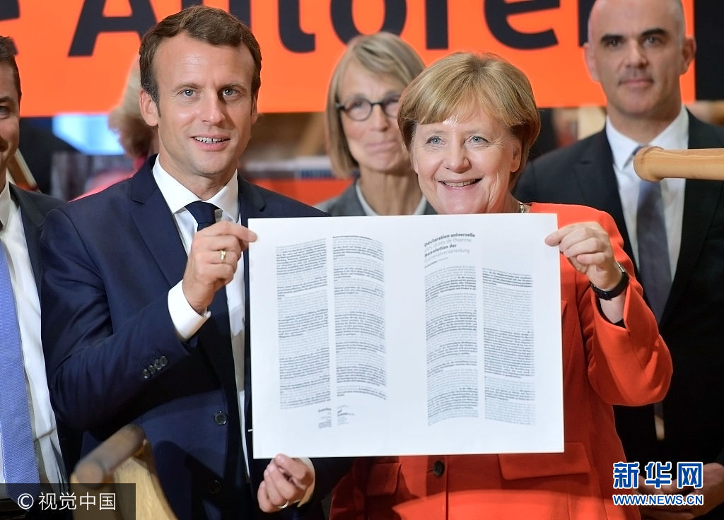 当地时间2017年10月10日，德国法兰克福，法兰克福书展开幕，法国总统马克龙与德国总理默克尔参观法国展示馆。第六十七届法兰克福书展将于2017年10月11日至15日举行。***_***FRANKFURT AM MAIN, GERMANY - OCTOBER 10: German Chancellor Angela Merkel and French President Emmanuel Macron hold the declaration of the human rights that was printed on an old print press during the opening of the Frankfurt Book Fair 2017 (Frankfurter Buchmesse) on October 10, 2017 in Frankfurt, Germany. The two leaders are known to have a good working relationship and share a number of policy views. The Frankfurt Book Fair will be open to the public from October 11-15.  (Photo by Thomas Lohnes/Getty Images)