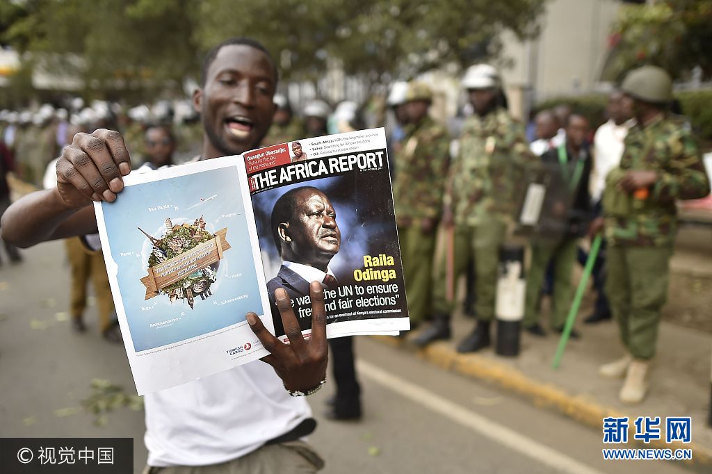 当地时间2017年10月11日，肯尼亚内罗毕，反对党国家超级联盟的支持者上街游行，抗议独立选举和边界委员会。***_***A supporter of the National Super Alliance (NASA) reads a magazine headlined with a photo of opposition leader in front of a police barricade in Nairobi on October 11, 2017 during street protests by NASA to call for the resignation of Independent Electoral and Boundaries Commission (IEBC) officials over claims of bungling the August presidential vote, which was nullified by the Supreme Court. Supporters of Kenya's opposition leader Raila Odinga took to the streets as poll officials mull their next move after his withdrawal from a presidential election plunged the country into uncharted waters. TONY KARUMBA