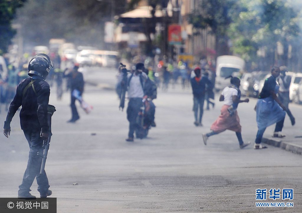当地时间2017年10月11日，肯尼亚内罗毕，反对党国家超级联盟的支持者上街游行，抗议独立选举和边界委员会。***_***A police officer walks through a cloud of teargas to disperse supporters of the National Super Alliance (NASA) in Nairobi on October 11, 2017 during street protests by NASA to call for the resignation of Independent Electoral and Boundaries Commission (IEBC) officials over claims of bungling the August presidential vote, which was nullified by the Supreme Court. Supporters of Kenya's opposition leader Raila Odinga took to the streets as poll officials mull their next move after his withdrawal from a presidential election plunged the country into uncharted waters. TONY KARUMBA