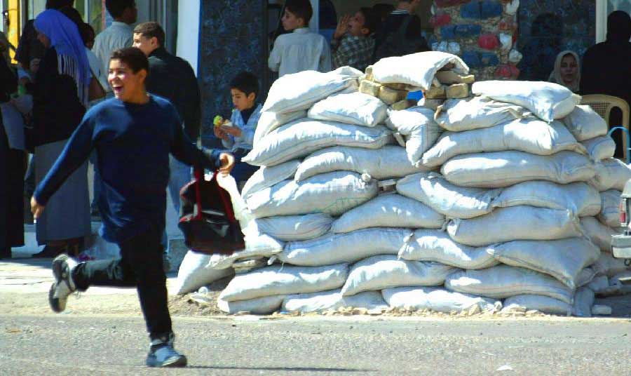 2003年3月，一名男孩从一处沙袋掩体前跑过。