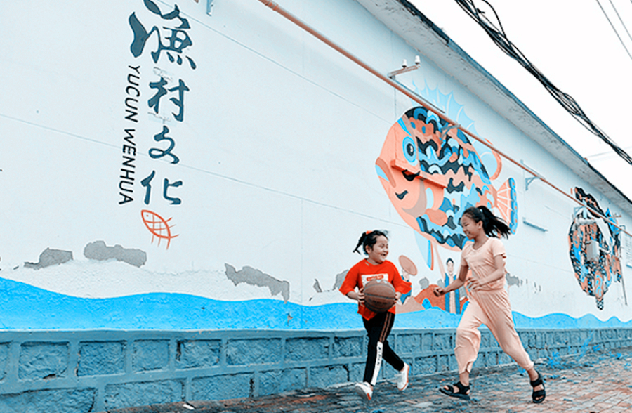 儿童在南排河镇渔村文化景观墙前玩耍.