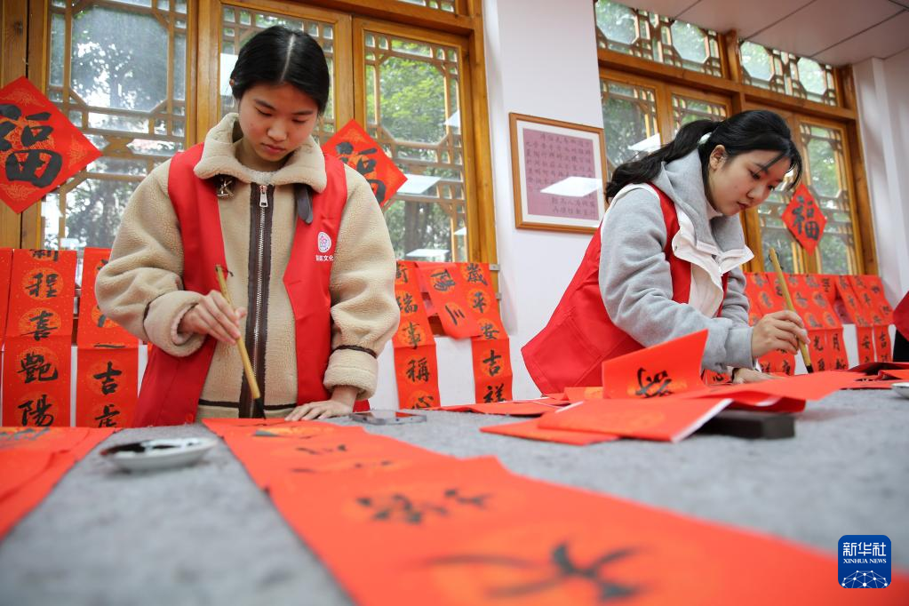 1月19日,四川省内江师范学院的大学生志愿者在书写春联.