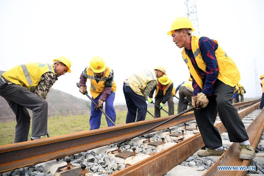 workers lay long tracks on railway section in yu