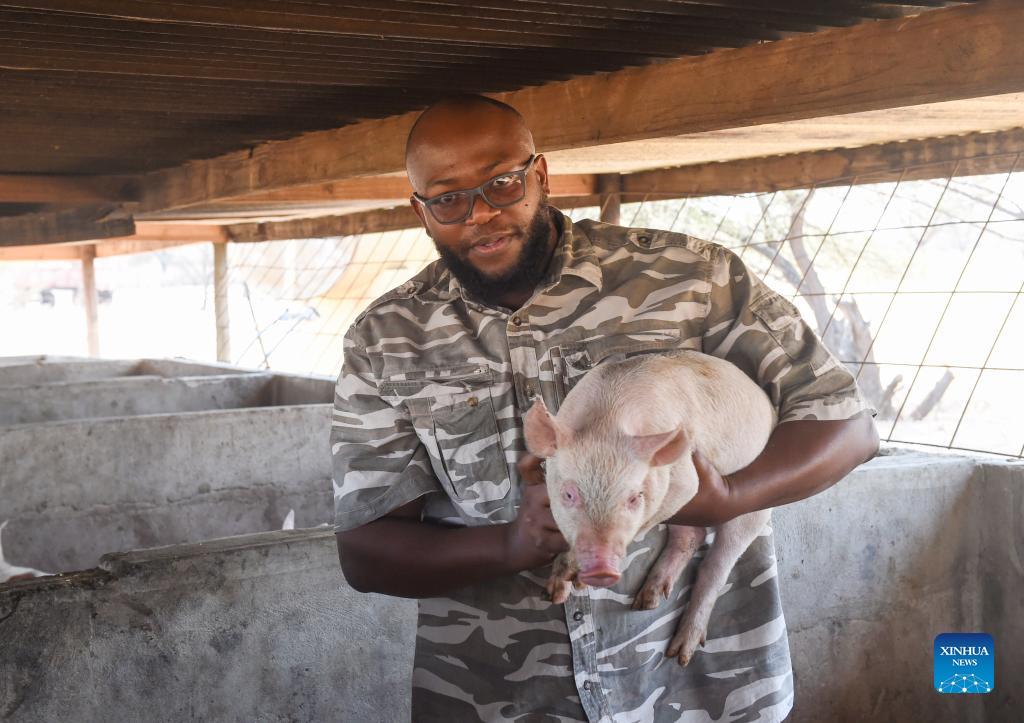 holds a piglet at his farm in molongwane, about 25 kilometers