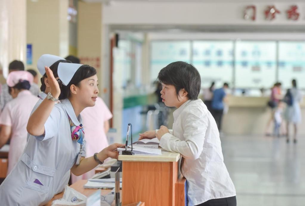 图为一名护士在服务台为患者导诊.