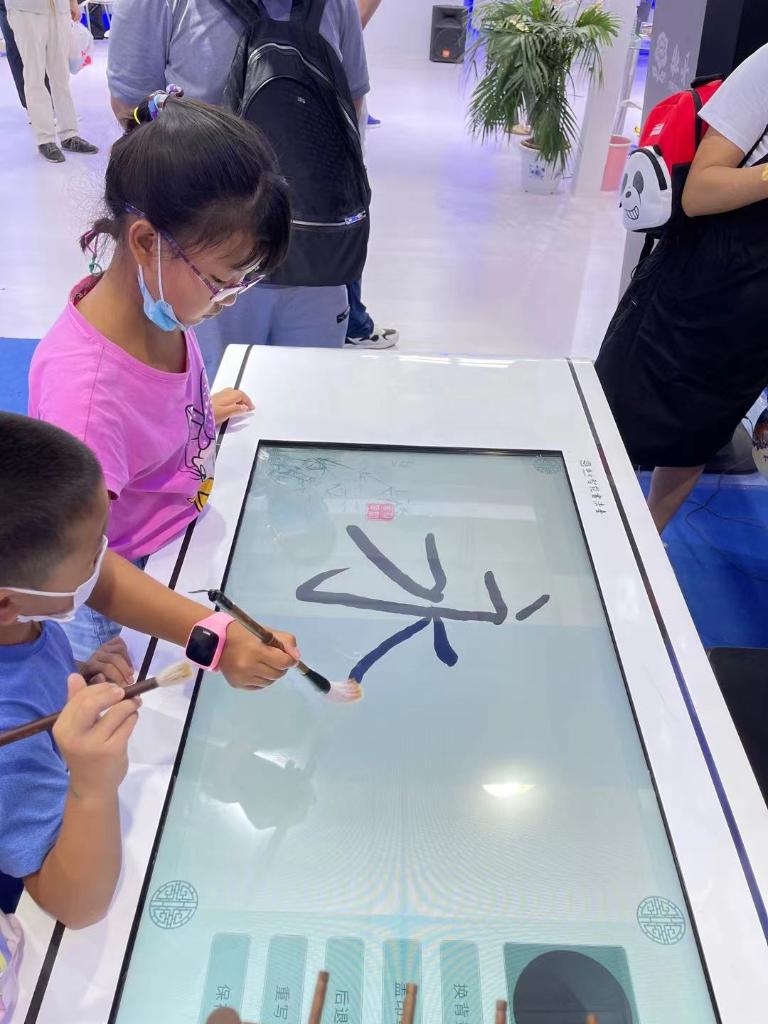 9月5日,在首钢园区文旅服务展馆内,一名小游客正在智能书法台上书写.