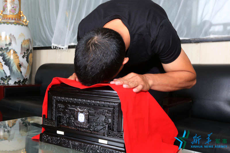 烈士申亮亮的哥哥申明明在永吉县殡仪馆伏在弟弟的骨灰盒上哭泣