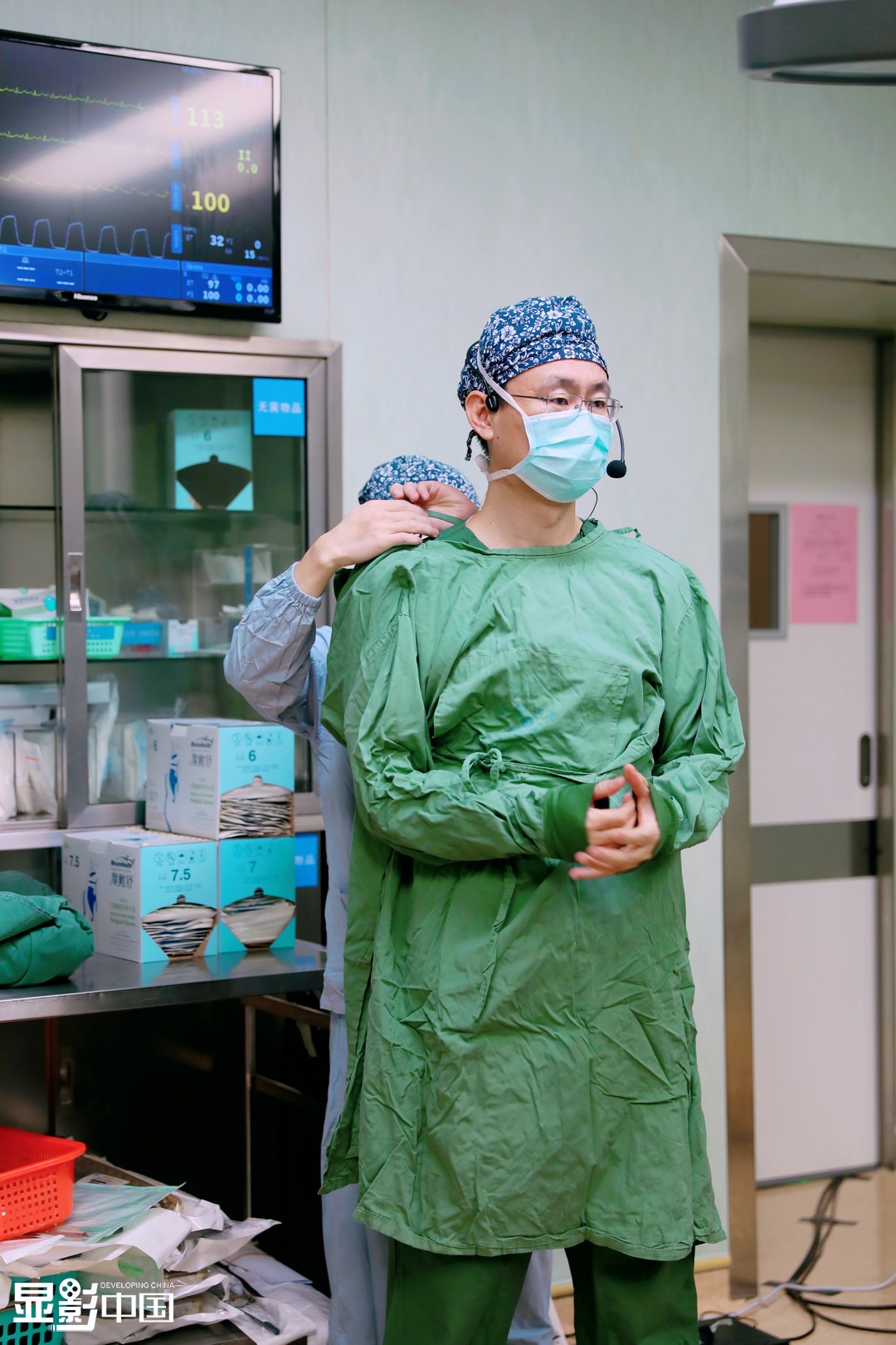 图为助理在术前帮范军强穿戴好手术服.